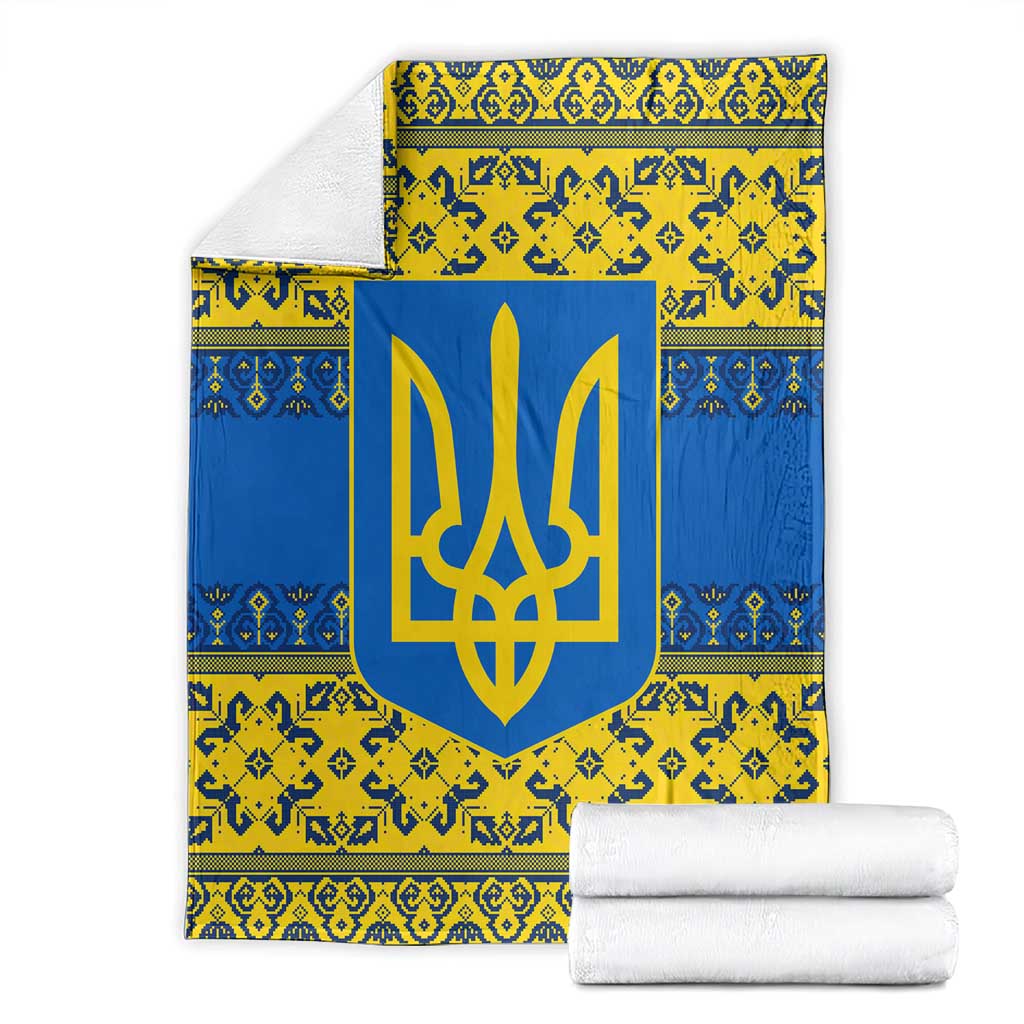 Blue and yellow patterned blanket with gold trident emblem, folded with white towels