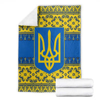Blue and yellow patterned blanket with gold trident emblem, folded with white towels