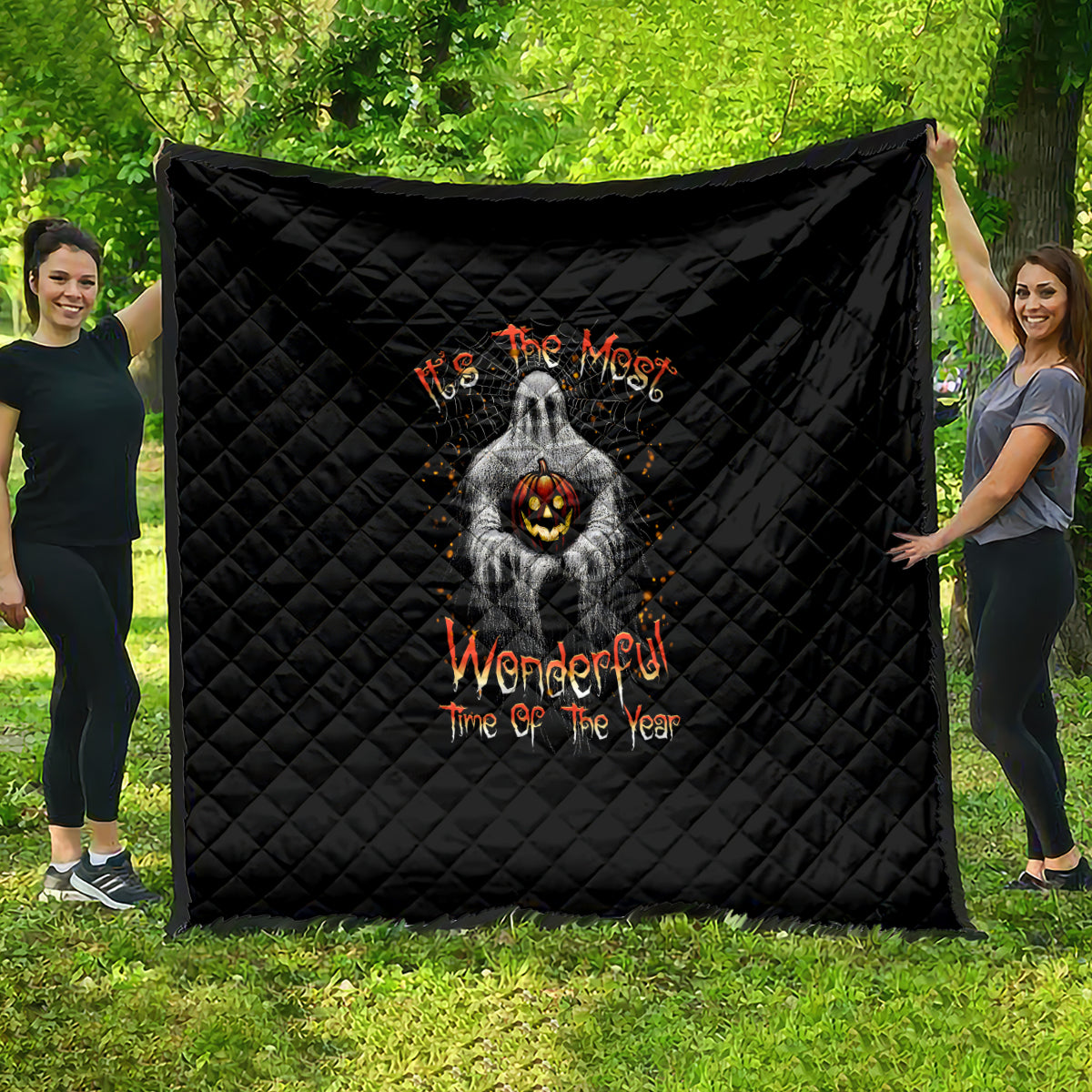 Black quilt with diamond stitching and spooky ghost holding jack-o-lantern, orange lettering