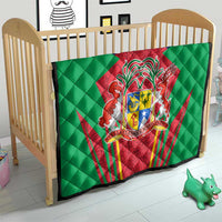 Green quilted crib blanket with central red crest shield emblem and quilted diamond pattern.