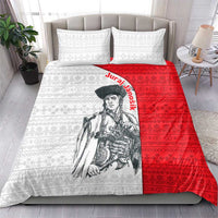 Red and white folk pattern quilt with warrior portrait, matching pillowcases on bed