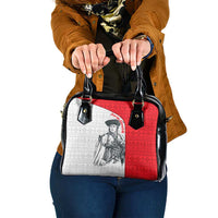 Shoulder handbag with red and white folk-style panel, black top handles and buckles