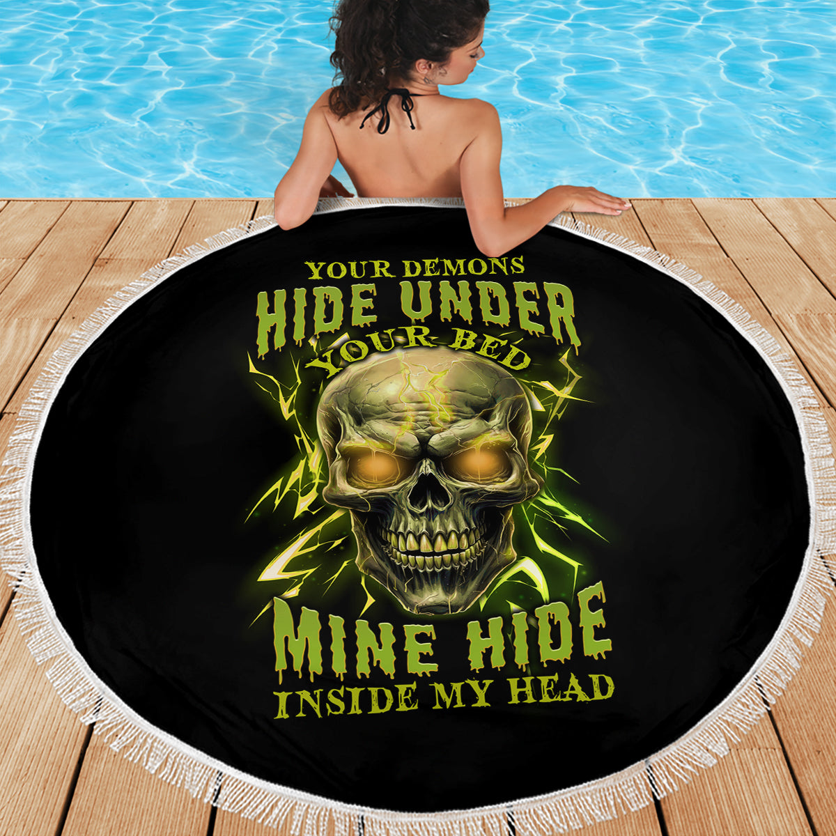 Round black beach blanket featuring neon green skull print and white tassel fringe