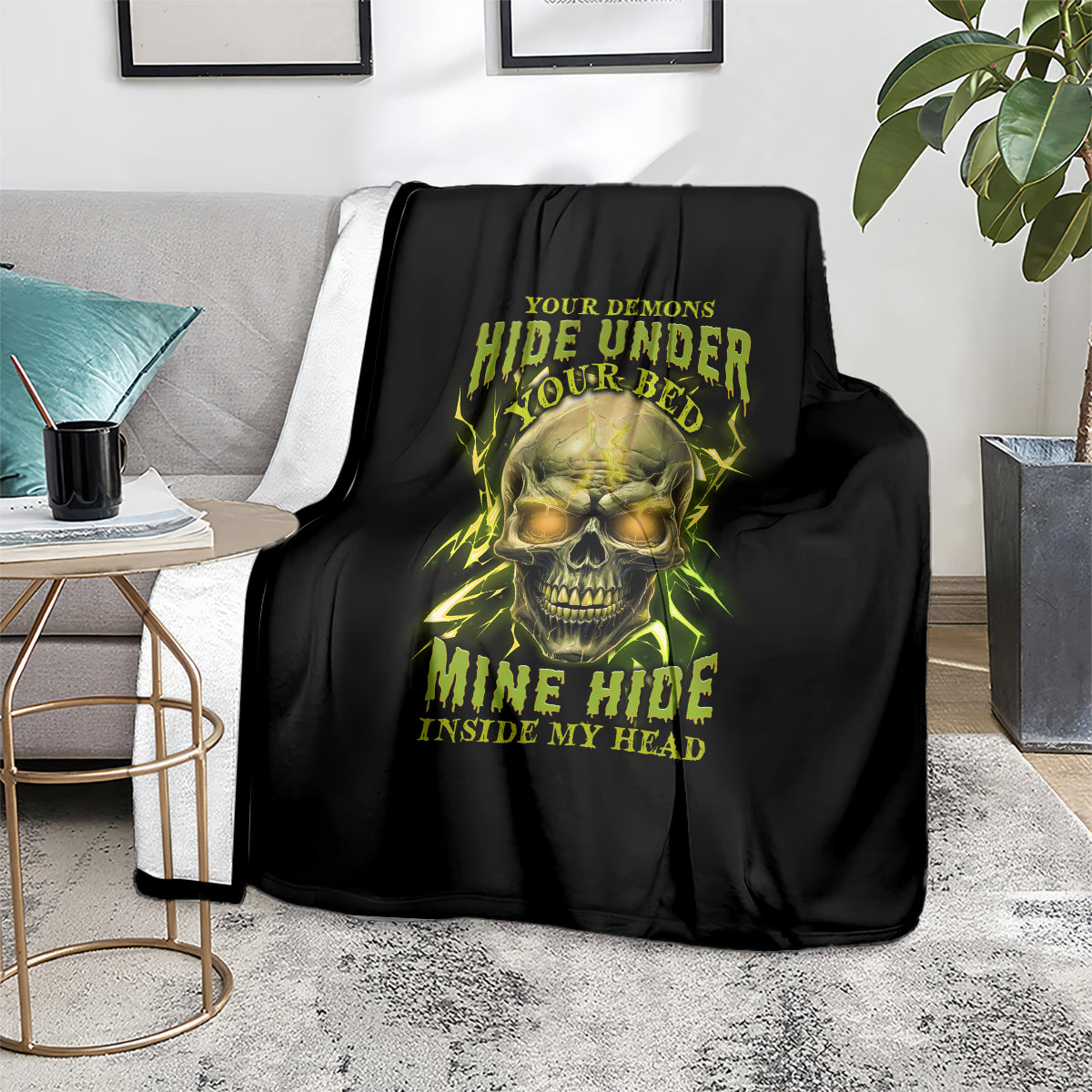 Black throw blanket on sofa with neon skull graphic, yellow-green horror lettering
