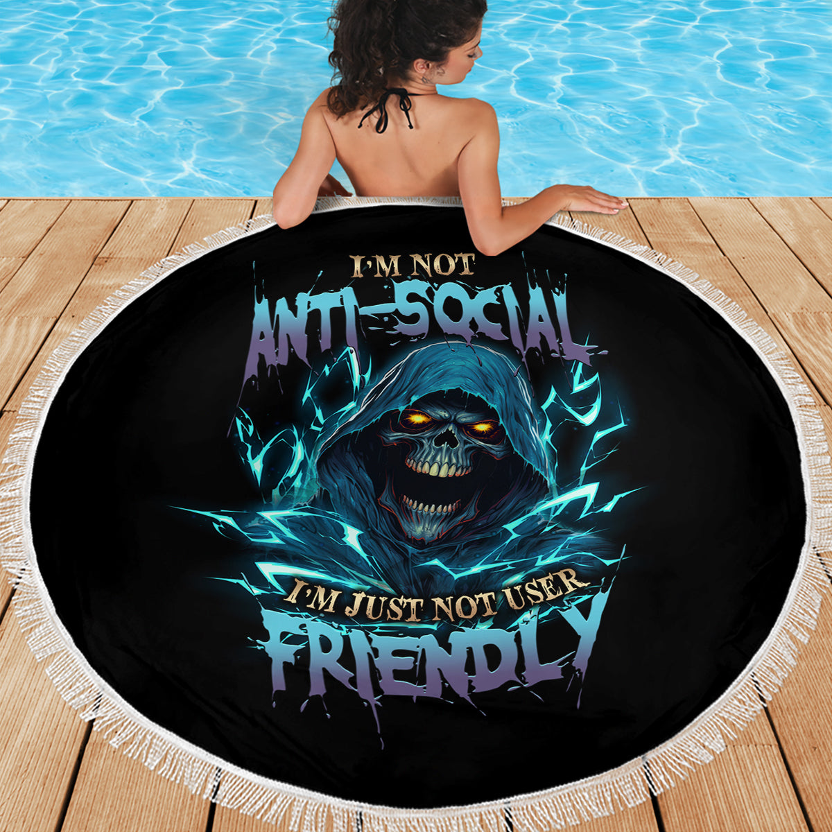 Round beach blanket with blue skull graphic and white fringed border, viewed from back