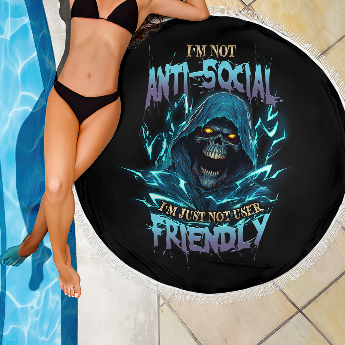 Round beach blanket with blue skull graphic on black, white fringe, draped by model