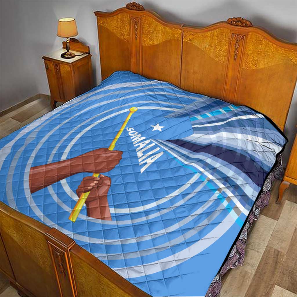 Blue and white Somalia flag quilt with raised fist and spear graphic on bed