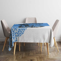Blue and white tablecloth on square table with chair backs visible