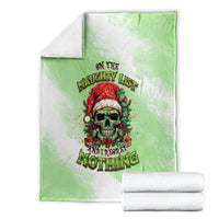Christmas blanket folded: green throw with skull Santa graphic, stacked with white towels
