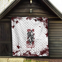 Skull quilt blanket displayed indoors, white base with dark red splatter and lettering