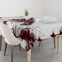 Skull tablecloth with maroon paint-splatter print, draped over dining table center