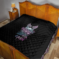 Black quilt on bed with diamond stitching and skull-wing rose graphic at center.