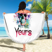 White round beach blanket with colorful skull graphic and fringed trim, held out