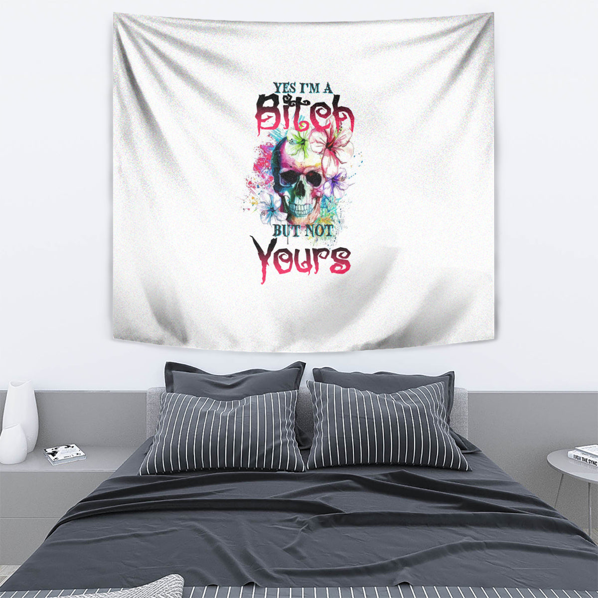 Multicolor skull graphic tapestry with bold text, hanging above a bed