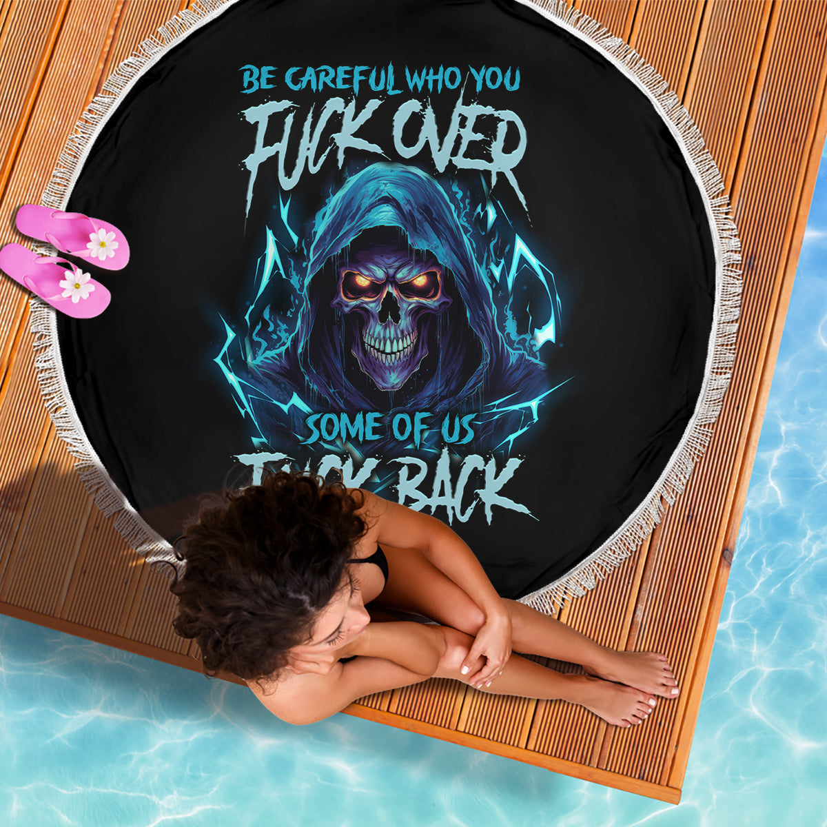 Round black beach blanket with blue skull graphic and white fringed edge