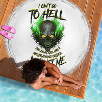 Round white beach blanket with green skull artwork and fringe border, on woven mat
