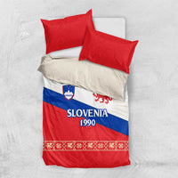 Duvet cover on light bedding with two red pillows; Slovenia 1990 dragon emblem
