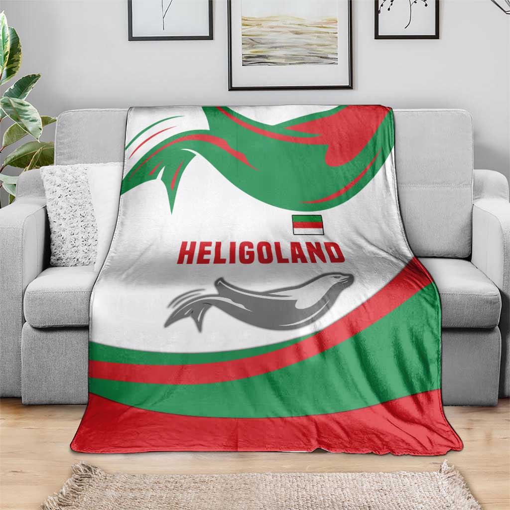 Green red white throw blanket with HELIGOLAND lettering and seal graphic, laid on sofa