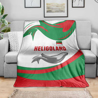 Green red white throw blanket with HELIGOLAND lettering and seal graphic, laid on sofa