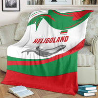 Green red white blanket with HELIGOLAND text and seal graphic, folded on an armchair