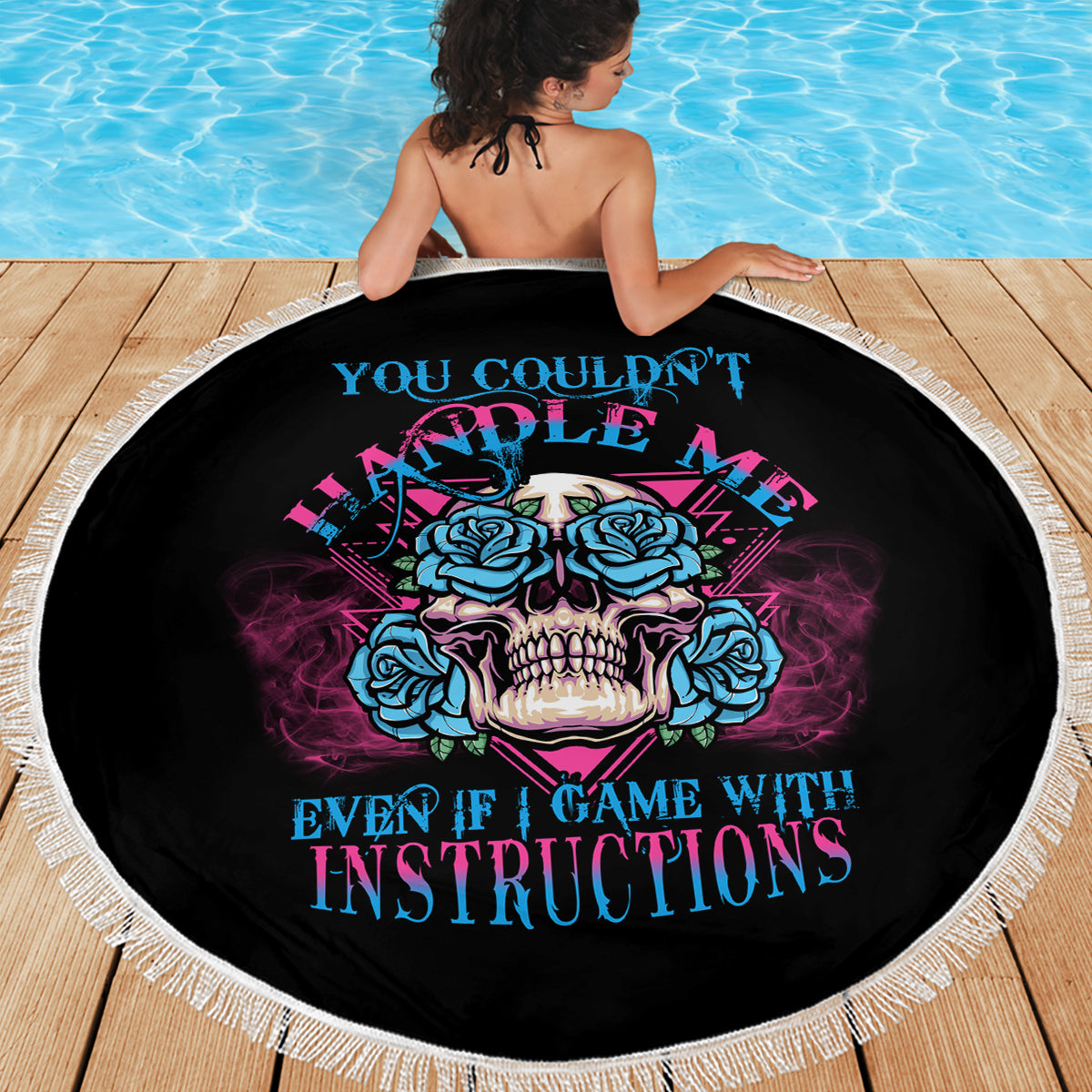 Back-facing beach blanket showing blue-and-pink skull print on black, fringe edge