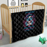 Black quilt with diamond stitching and blue/pink skull artwork on baby bed