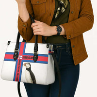 White tote bag with black handles, red/blue cross stripe, puffin graphic panel