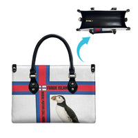 White tote bag with black handles and open interior, red/blue cross stripe, puffin