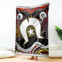 Multicolor Aboriginal pattern blanket draped on floor, black-and-red circular design