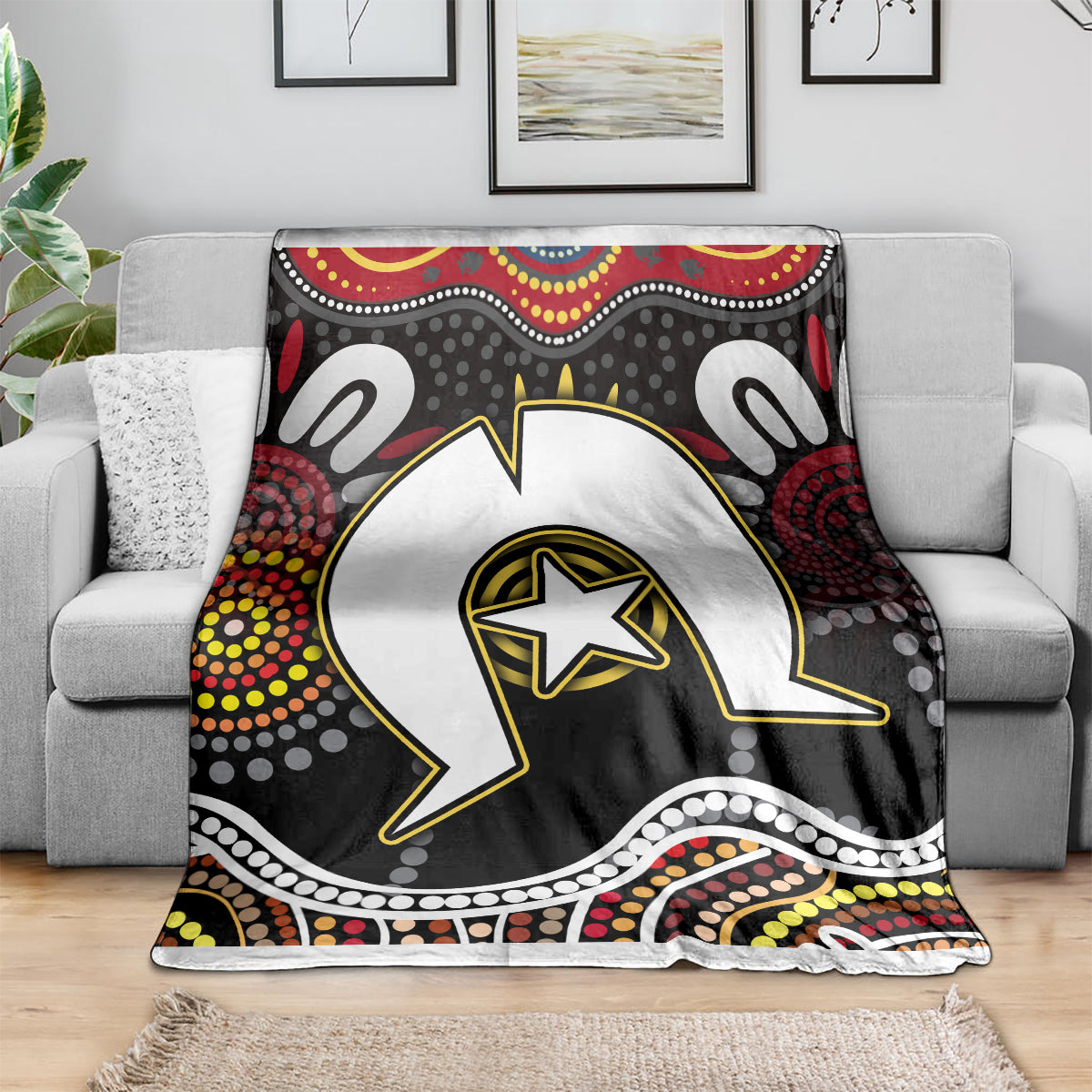 Multicolor Aboriginal pattern blanket on gray sofa with large white-and-black animal graphic