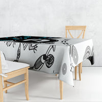 Aboriginal pattern tablecloth draped over table, black linework and circular teal accents