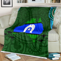 Green Aboriginal throw blanket with central flag graphic, draped over sofa back