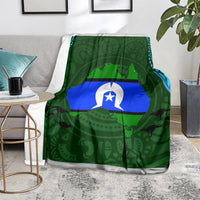 Green throw blanket with central flag graphic and Aboriginal pattern, draped on couch
