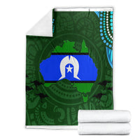 Green throw blanket folded, featuring central flag graphic and teal dotted border