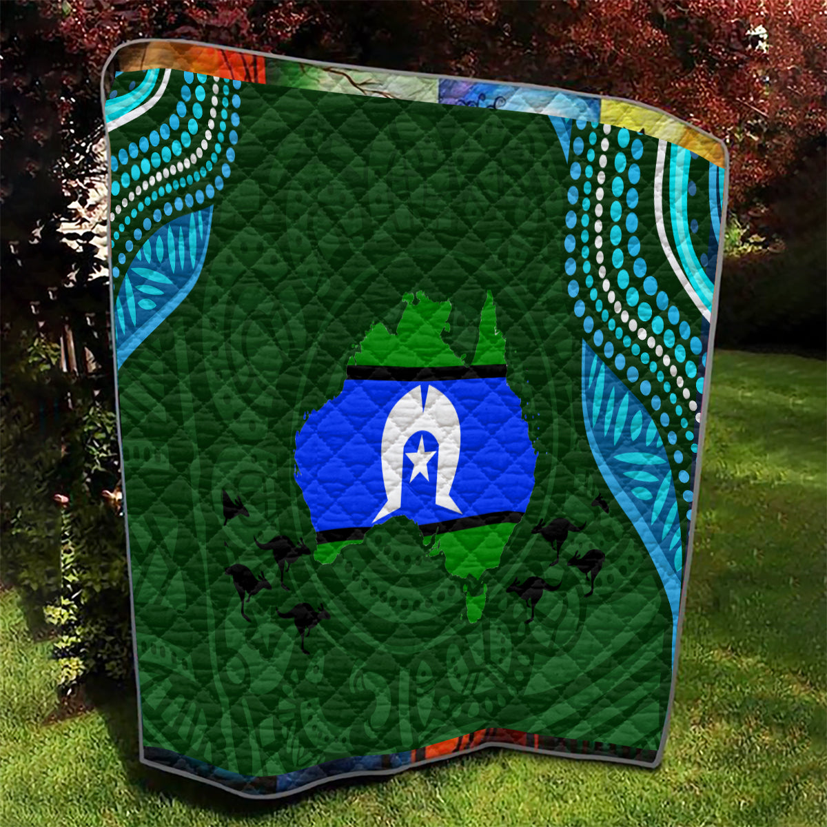 Green diamond-quilted blanket with central blue emblem and teal wave dot accents