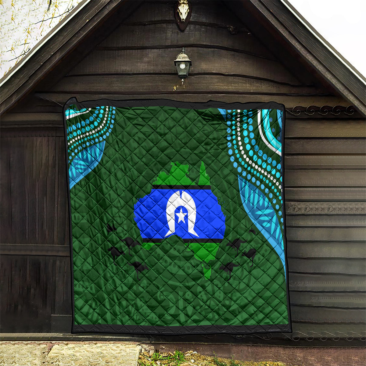 Green patterned quilt with diamond quilting, blue island emblem and teal dotted corner details