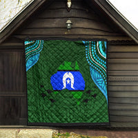 Green patterned quilt with diamond quilting, blue island emblem and teal dotted corner details
