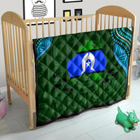 Green nursery quilt with blue island emblem, teal swirls, and black-and-white border edge