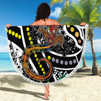 Fringed round beach blanket with multicolor lizard dot-art pattern held up on sand