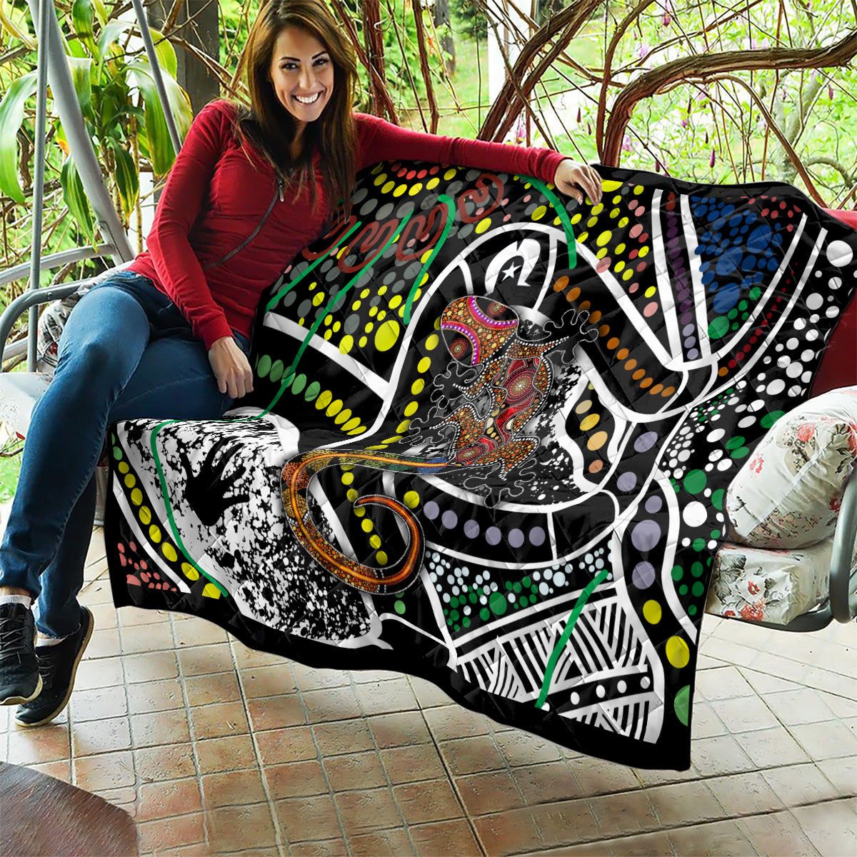 Multicolor Aboriginal lizard pattern dot art quilt held on a porch with large graphic