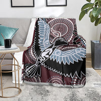 Bird pattern blanket on couch, maroon base with black, light blue and white tribal motifs