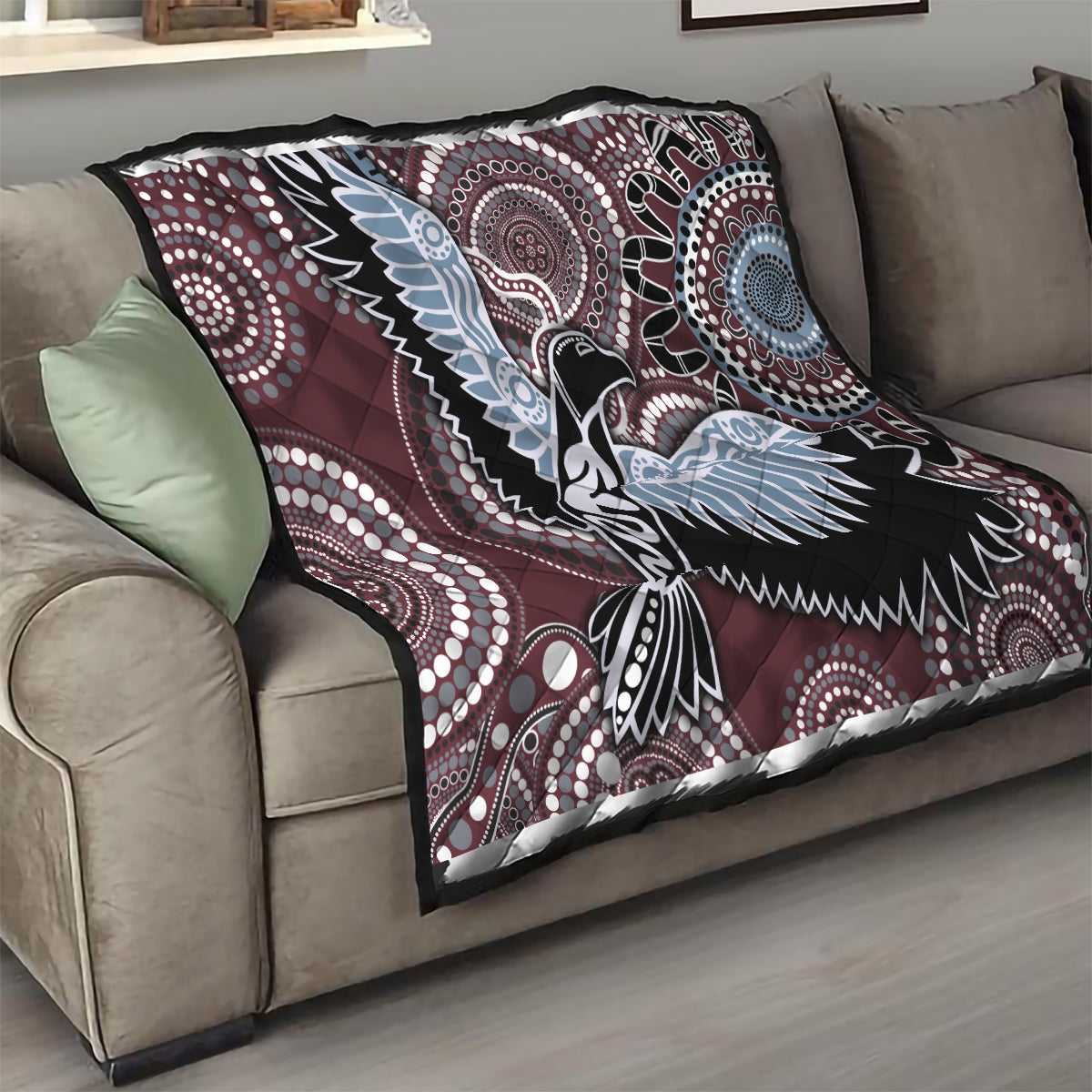 Burgundy bird pattern quilt draped on a sofa, featuring light-blue wings and black-and-white circles