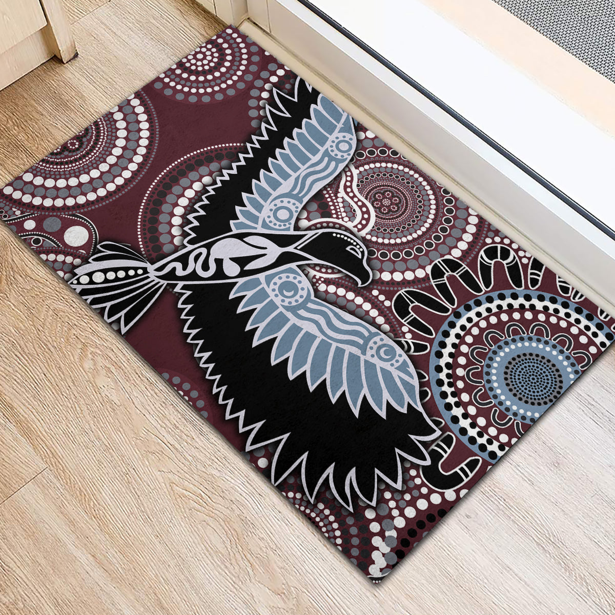 Maroon rubber doormat featuring Aboriginal-style bird wings, outlined in white and blue
