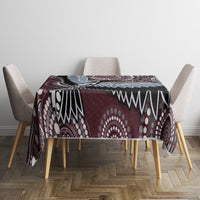 Bird-pattern tablecloth covering a table center, maroon and black with blue and white details.