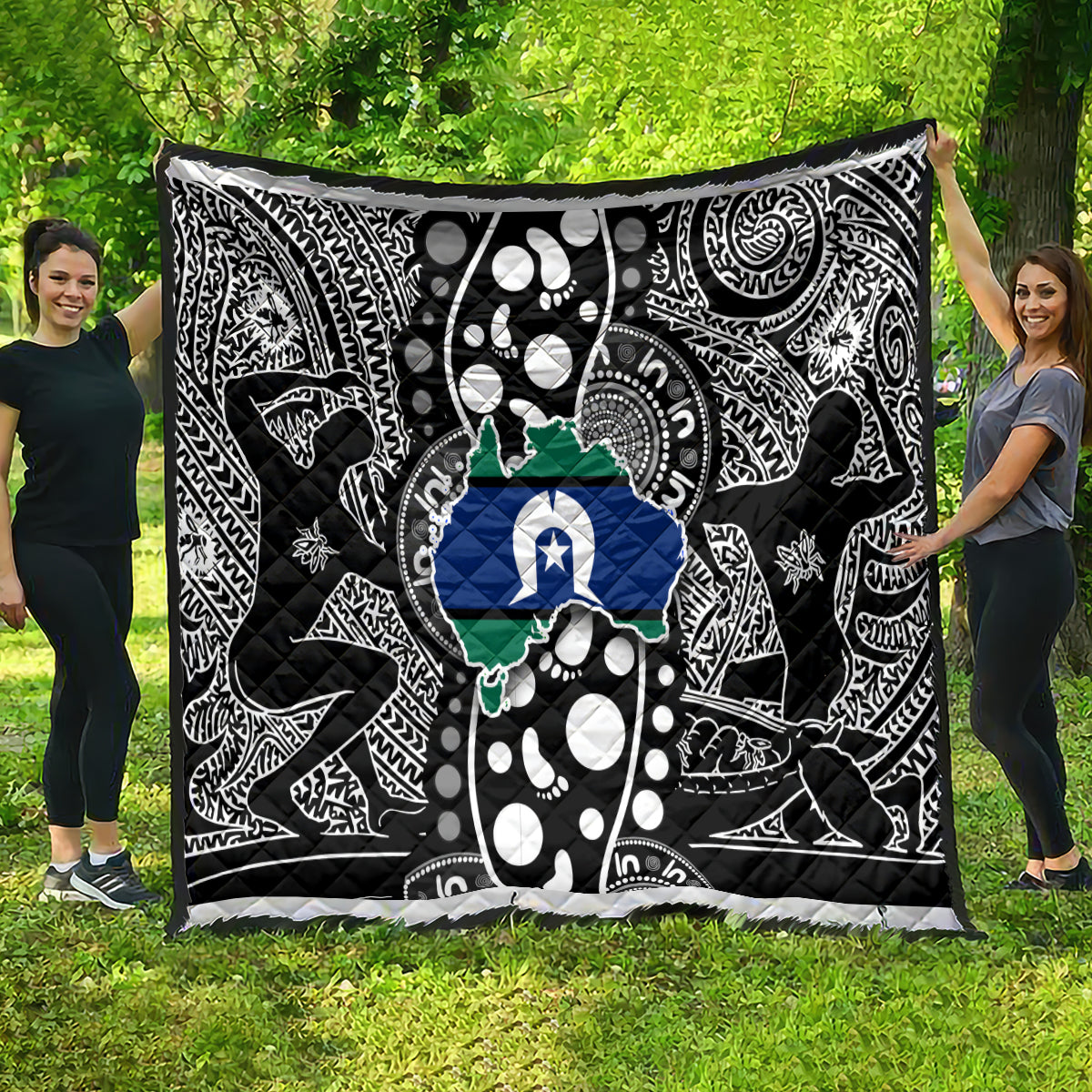 Aboriginal pattern quilt spread on grass, black-and-white motifs with blue star and green map