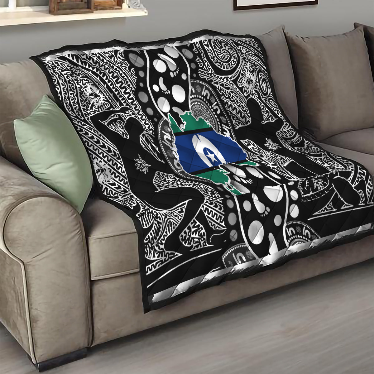 Aboriginal pattern quilt draped on sofa, black-and-white motifs with blue star and green map center