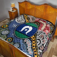 Multicolor Aboriginal pattern quilt draped on bed, oval star emblem in blue and green
