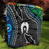 Multicolor aboriginal style quilt on grass with black, white, blue and green geometric detailing