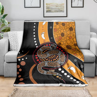 Multicolor snake dot art blanket spread across a sofa, showing bold serpent design.