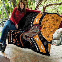 Snake dot art quilt draped on a couch, showing black, orange, and red paw-print motifs